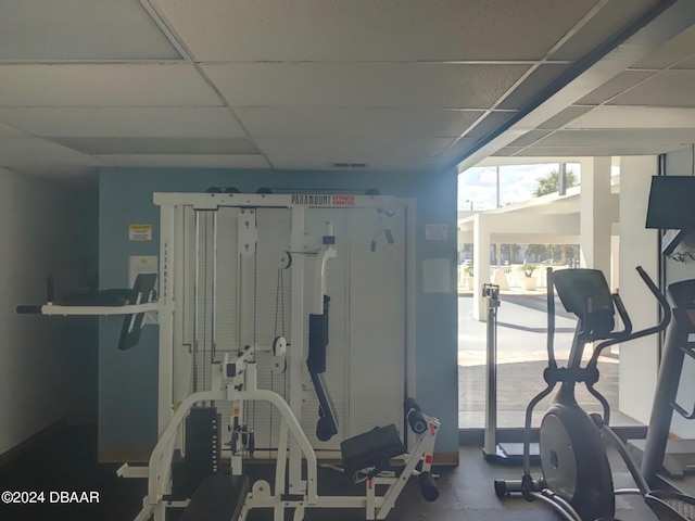 exercise room with a paneled ceiling and a wall of windows