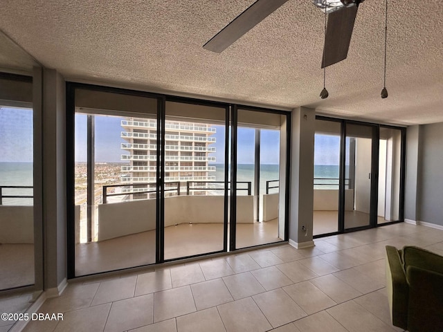 interior space featuring a textured ceiling, light tile patterned flooring, baseboards, and floor to ceiling windows