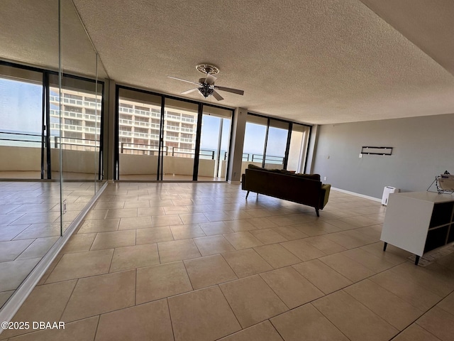 unfurnished living room with tile patterned flooring, floor to ceiling windows, and ceiling fan