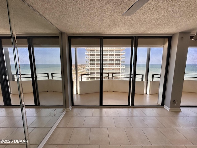 doorway featuring a water view, baseboards, a wall of windows, and a textured ceiling