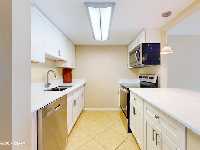 kitchen with stainless steel appliances, a sink, white cabinetry, light countertops, and decorative light fixtures