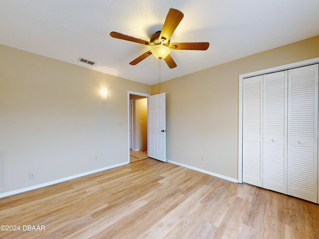 unfurnished bedroom featuring baseboards, a closet, visible vents, and light wood-style floors