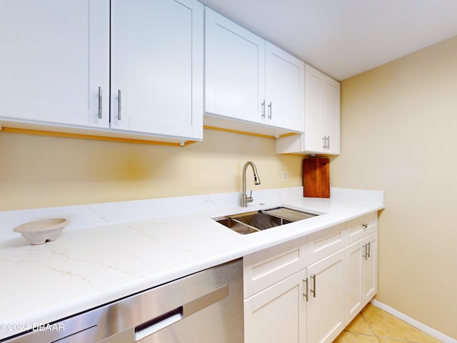 kitchen with white cabinets, light stone counters, sink, light tile patterned floors, and dishwasher