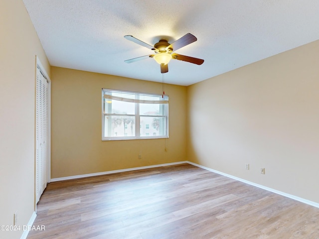 unfurnished bedroom featuring ceiling fan, light wood-type flooring, a textured ceiling, and a closet