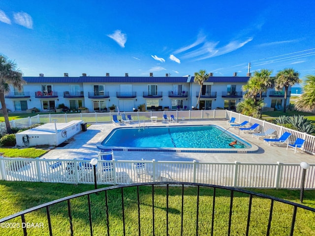 pool with a patio area, a residential view, fence, and a yard