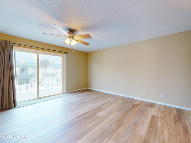 spare room featuring a textured ceiling, light wood finished floors, a ceiling fan, and baseboards