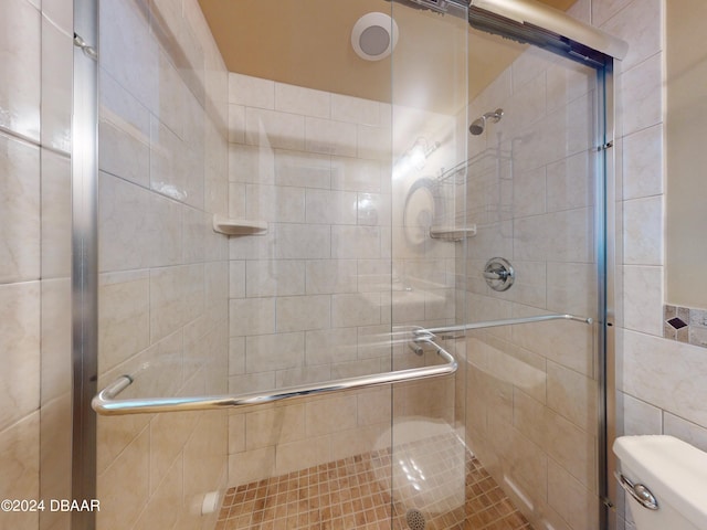 full bathroom featuring a shower stall and toilet