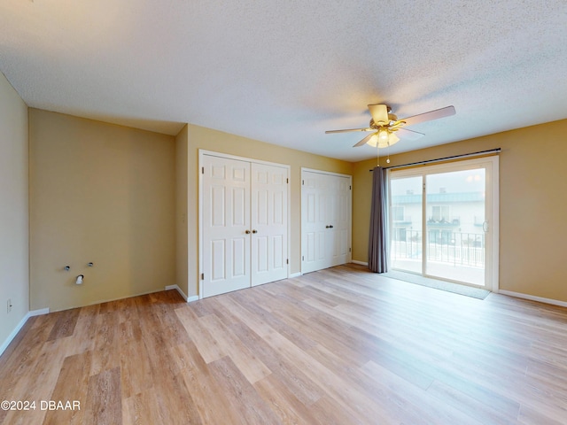 unfurnished bedroom featuring access to outside, light hardwood / wood-style flooring, ceiling fan, a textured ceiling, and multiple closets