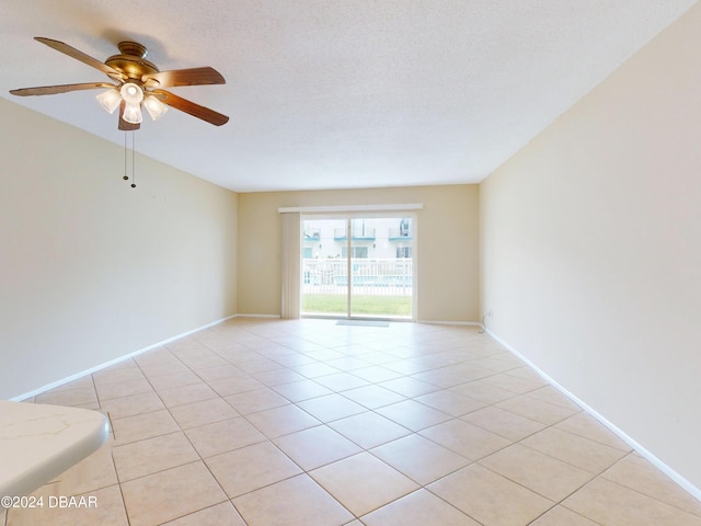 unfurnished room featuring light tile patterned floors, baseboards, and a textured ceiling