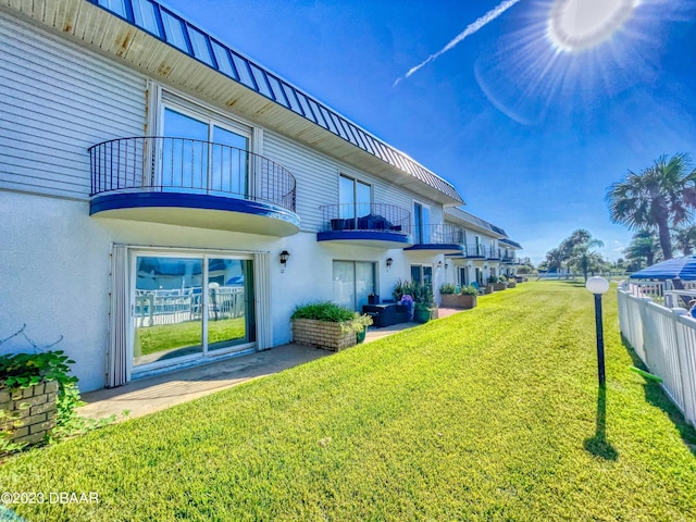 back of property featuring a patio, a balcony, and a lawn