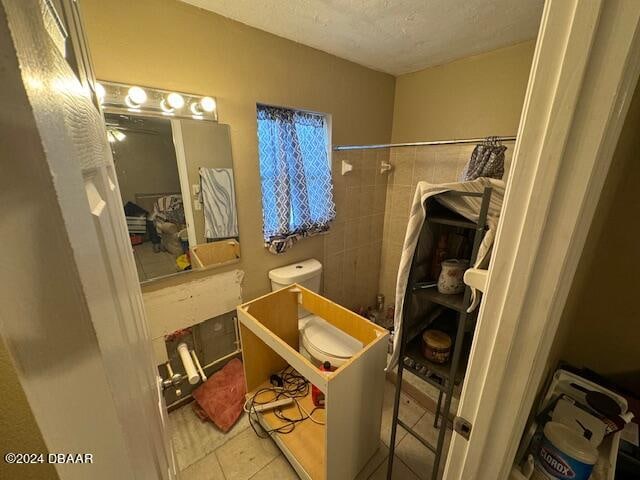 bathroom featuring toilet, a textured ceiling, and tile patterned flooring