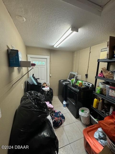 laundry area with light tile patterned flooring, a textured ceiling, and separate washer and dryer