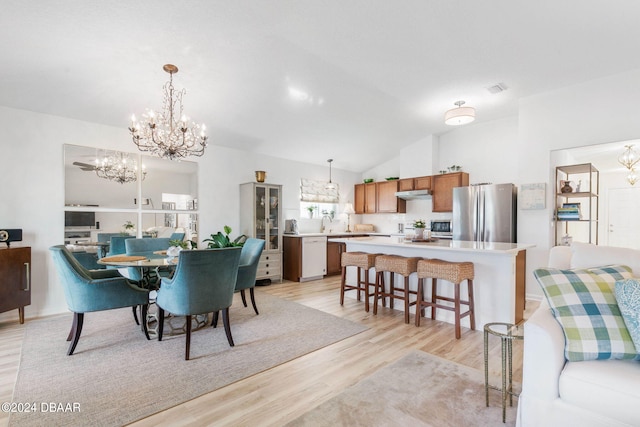 dining space with light hardwood / wood-style floors, sink, vaulted ceiling, and a notable chandelier