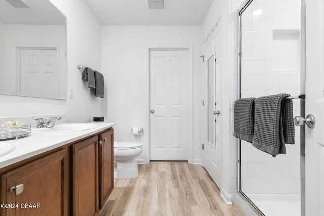 bathroom featuring wood-type flooring, vanity, a shower with door, and toilet