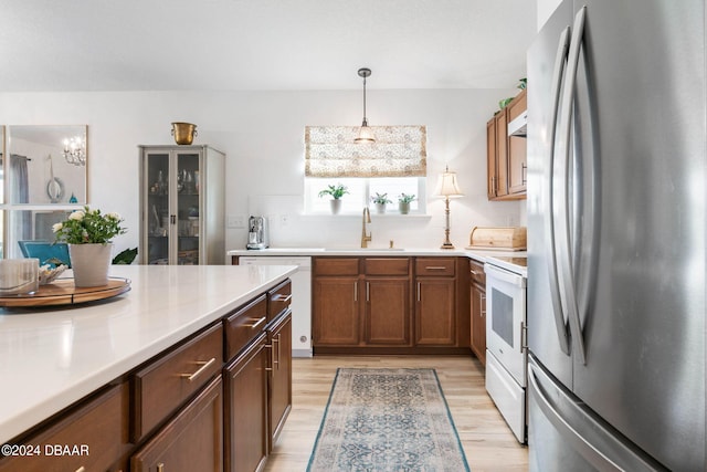 kitchen featuring light wood-type flooring, white appliances, sink, and an inviting chandelier