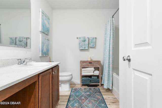 full bathroom featuring wood-type flooring, vanity, toilet, and shower / tub combo with curtain