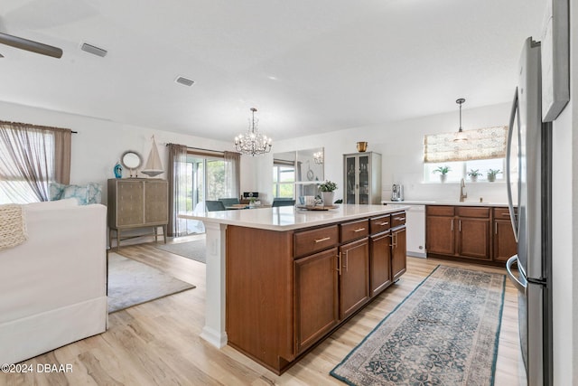 kitchen featuring light hardwood / wood-style floors, hanging light fixtures, a kitchen island, and stainless steel fridge