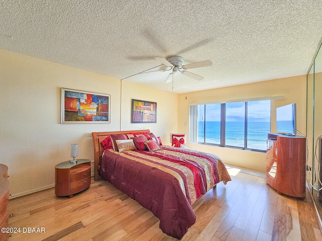 bedroom featuring ceiling fan, a textured ceiling, and light wood-type flooring