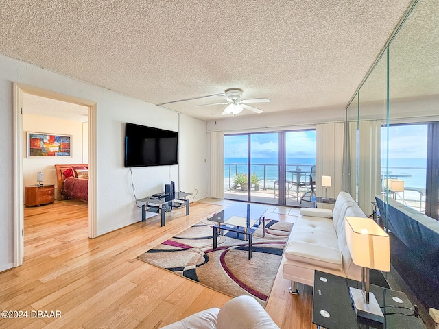 living room featuring light hardwood / wood-style floors, ceiling fan, and a textured ceiling