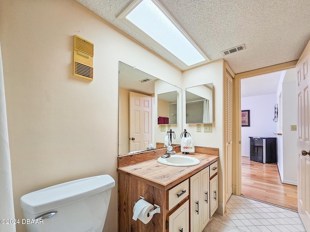 bathroom featuring tile patterned flooring, vanity, a textured ceiling, and toilet