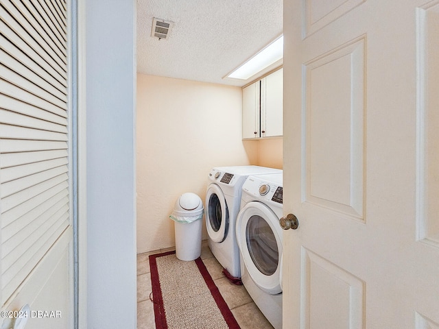 washroom featuring cabinets, separate washer and dryer, a textured ceiling, and light tile patterned floors