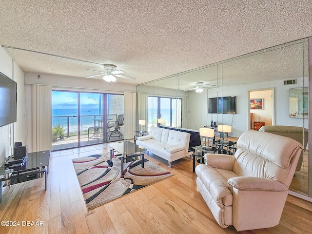 living room with hardwood / wood-style flooring, ceiling fan, and a textured ceiling