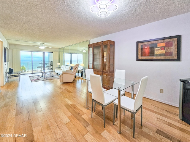 dining space with a textured ceiling, light wood-type flooring, and ceiling fan