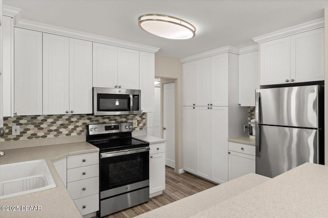 1010/1020 Big Tree Rd, Daytona Beach, FL 32119 - kitchen featuring appliances with stainless steel finishes, backsplash, light countertops, wood finished floors, and white cabinetry