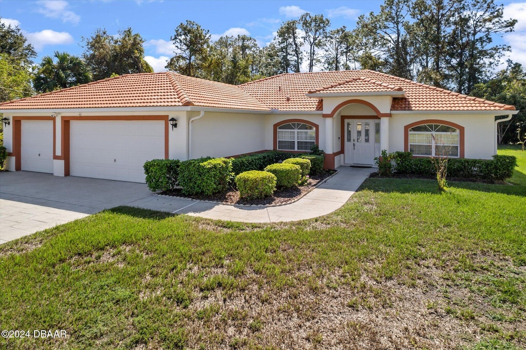 mediterranean / spanish-style house featuring a garage and a front yard