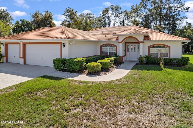 mediterranean / spanish-style house featuring a garage and a front yard