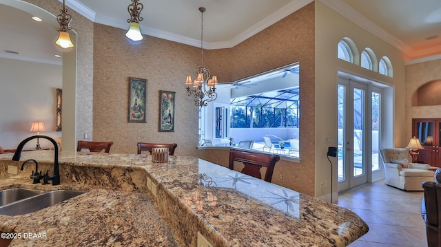 kitchen featuring a high ceiling, tile patterned floors, sink, ornamental molding, and decorative light fixtures