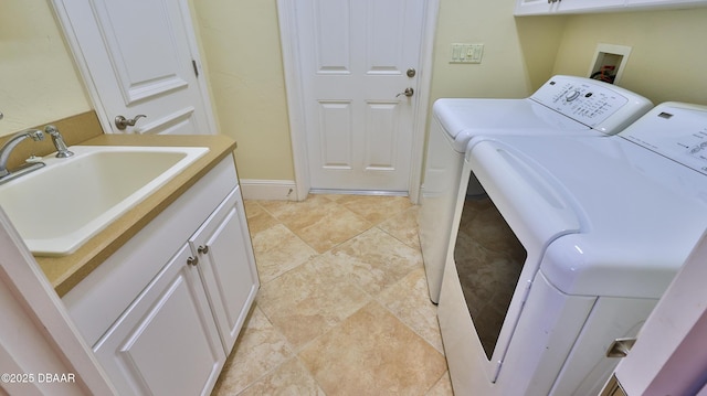 washroom with cabinets, washing machine and dryer, and sink