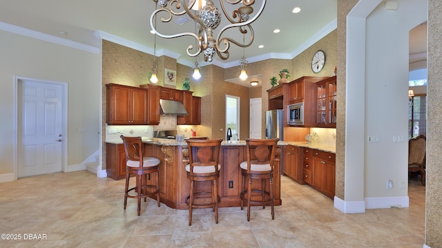 kitchen featuring stainless steel microwave, a kitchen breakfast bar, ornamental molding, a kitchen island, and a chandelier