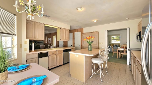 kitchen with a center island, a chandelier, dishwasher, light countertops, and a sink