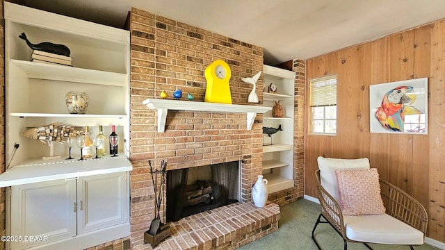 carpeted living area with built in features, wood walls, and a fireplace