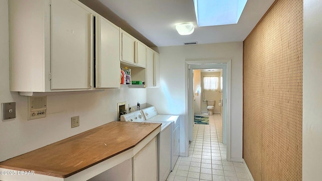 washroom featuring visible vents, washing machine and clothes dryer, a skylight, light tile patterned flooring, and cabinet space