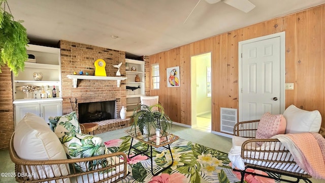 living room featuring visible vents, wooden walls, a brick fireplace, and carpet flooring