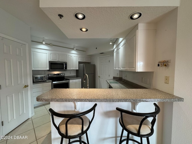 kitchen featuring appliances with stainless steel finishes, kitchen peninsula, a breakfast bar area, and white cabinets