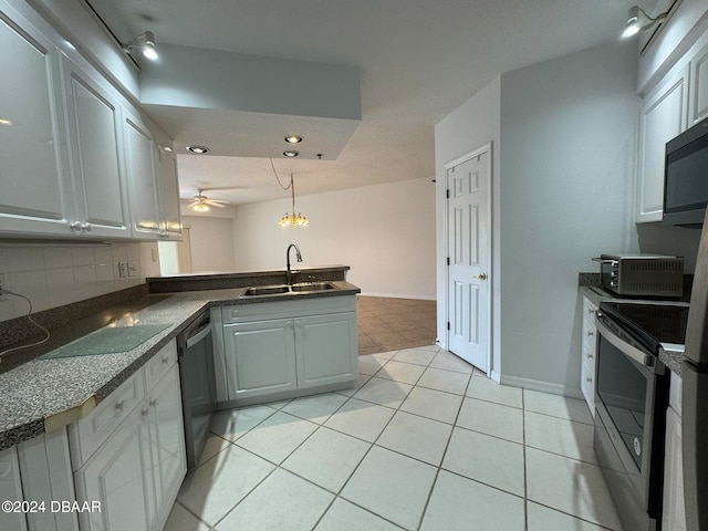 kitchen with sink, appliances with stainless steel finishes, kitchen peninsula, pendant lighting, and backsplash