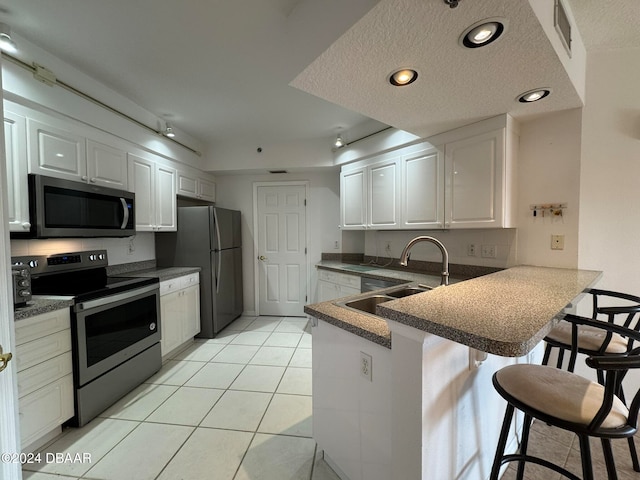 kitchen with a kitchen bar, kitchen peninsula, white cabinets, and appliances with stainless steel finishes