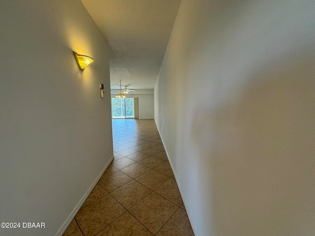 hall with light tile patterned floors and a textured ceiling