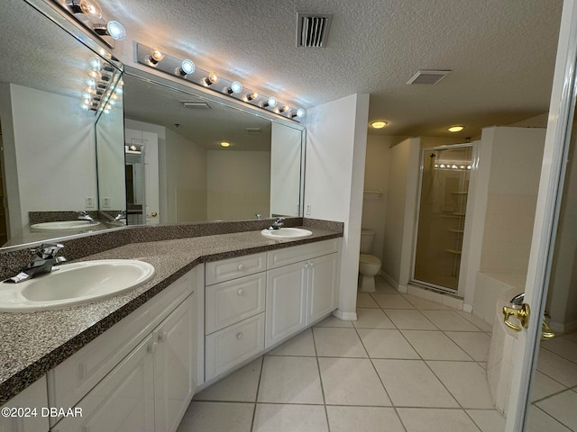 bathroom featuring a shower with door, vanity, a textured ceiling, tile patterned floors, and toilet