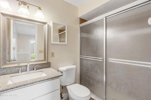 bathroom with vanity, a shower with door, and toilet