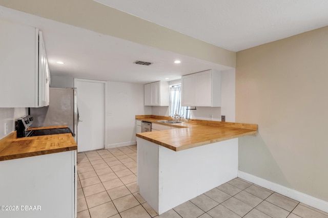 kitchen with white cabinetry, light tile patterned floors, wood counters, and kitchen peninsula