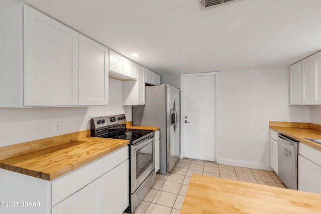 kitchen with butcher block countertops, stainless steel appliances, white cabinets, and light tile patterned flooring