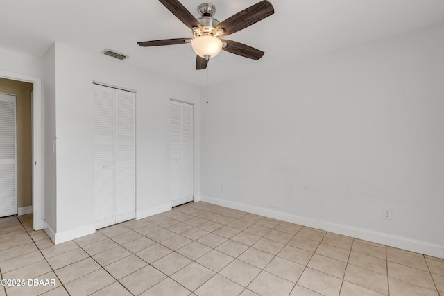 unfurnished bedroom featuring multiple closets and ceiling fan