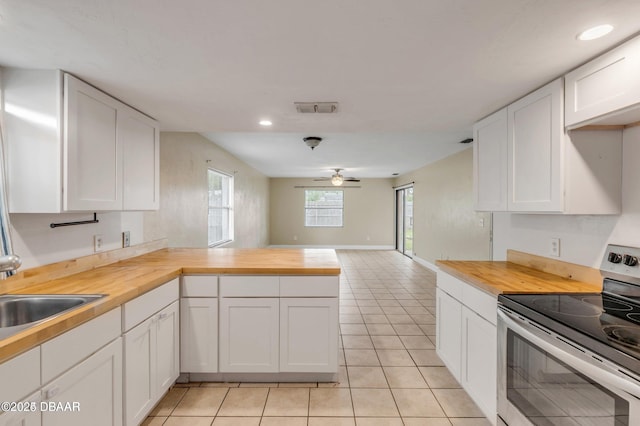 kitchen with stainless steel electric stove, wood counters, white cabinetry, sink, and light tile patterned floors