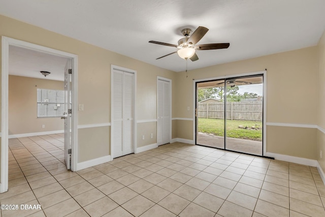 unfurnished bedroom with access to outside, two closets, ceiling fan, and light tile patterned floors