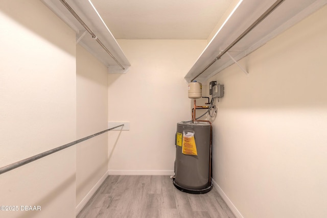 walk in closet featuring light wood-style floors and water heater