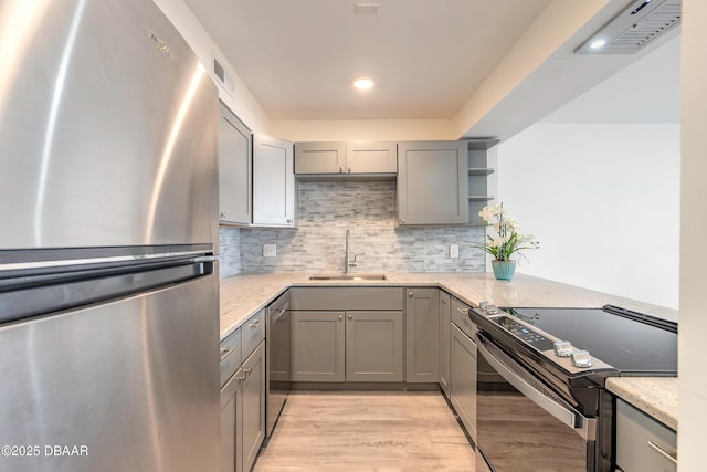 kitchen with visible vents, light stone countertops, gray cabinets, appliances with stainless steel finishes, and a sink